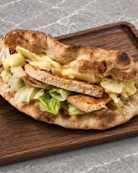Focaccia με κοτόπουλο, μαρούλι και κρέμα τυριού σε ξύλινο δίσκο